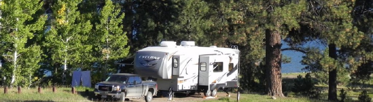 Cyclone Fifth Wheel being towed by a GMC truck through a wooded area